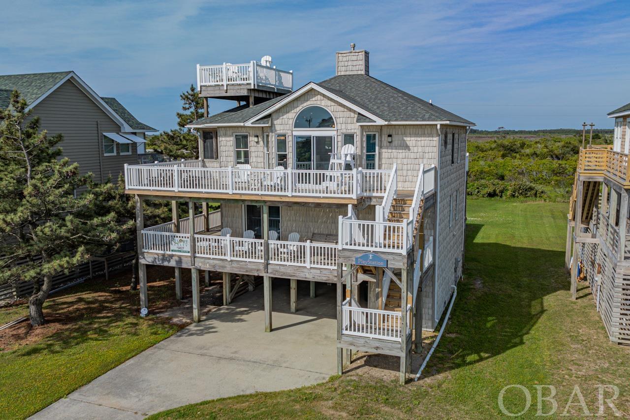 Welcome to your dream coastal retreat in the heart of South Nags Head! This impeccably maintained 4-bedroom, 3.5-bathroom home, affectionately named "Playstation," is situated in a truly magical location. As a semi-oceanfront property, it offers easy beach access with stunning ocean and sunset views. Bordering the protected Cape Hatteras National Seashore to the west, "Playstation" enjoys a private setting, perfect for those seeking tranquility amidst the coastal beauty. The first floor of "Playstation" features new furnishings and LVP flooring throughout, with a second sitting area that provides additional space. This level boasts three bedrooms, offering versatile sleeping arrangements for guests. The King Bedroom features a convenient jack and jill bath, shared with a charming bunk room, making it ideal for families. Additionally, the third bedroom boasts a Queen bed with deck access and its own bath, ensuring added comfort and convenience. Ascending to the upper level of "Playstation," you'll discover the essence of luxury living. A King ensuite awaits, featuring a double vanity and deck access, offering a serene retreat for relaxation. The main living area welcomes you with cathedral ceilings and an open floor plan, creating a spacious and airy atmosphere. A convenient half bath is nestled nearby, while a screen porch provides the perfect spot for enjoying the coastal breeze and ocean views. However, the crown jewel of this level is undoubtedly the sky deck, boasting panoramic vistas of the ocean and the adjacent national park, providing a breathtaking backdrop for unforgettable gatherings. From lounging by the private pool, complete with a new liner and ladder, to indulging in beachside bliss with just a short stroll to the lifeguarded East Indigo Street beach access, "Playstation" offers unparalleled coastal living. Residents will also have exclusive access to community amenities, including a pool and tennis courts. Located mere minutes from local attractions such as Fish Heads Bar & Grill, the outlet mall, and historic landmarks like Jennette's Pier and the Bodie Island Lighthouse, this home offers the perfect blend of convenience and coastal charm!