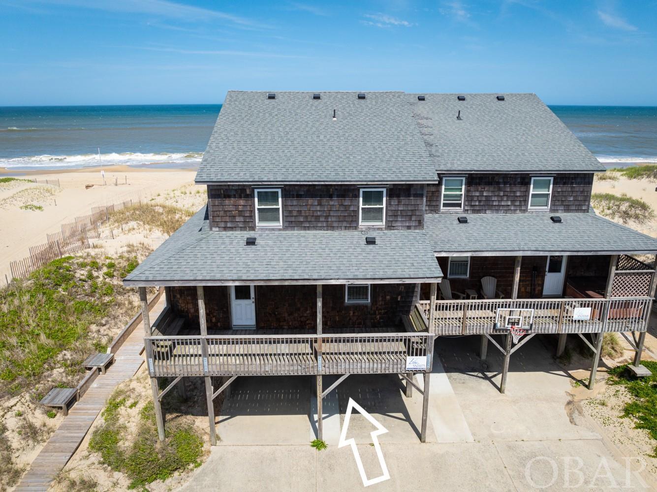 Enjoy everything quaint South Nags Head has to offer in this oceanfront property with beautiful ocean views. On the ground level you will find a dry entry, outdoor shower, and new hot tub in a private patio area for year-round enjoyment. Upon entering the main level you will find a spacious living room, dining area, kitchen, full bathroom, one bedroom, a private deck off the kitchen area, and plenty of east facing deck space to enjoy even more of the great views. The top level boasts a primary suite with a private porch and large tub, two additional bedrooms, and a bathroom. Property has been well maintained and some of the recent updates include new LVP flooring, fresh paint throughout, and new furnishings. Located adjacent to a lifeguard stand at Juncos St. in the summer months.
