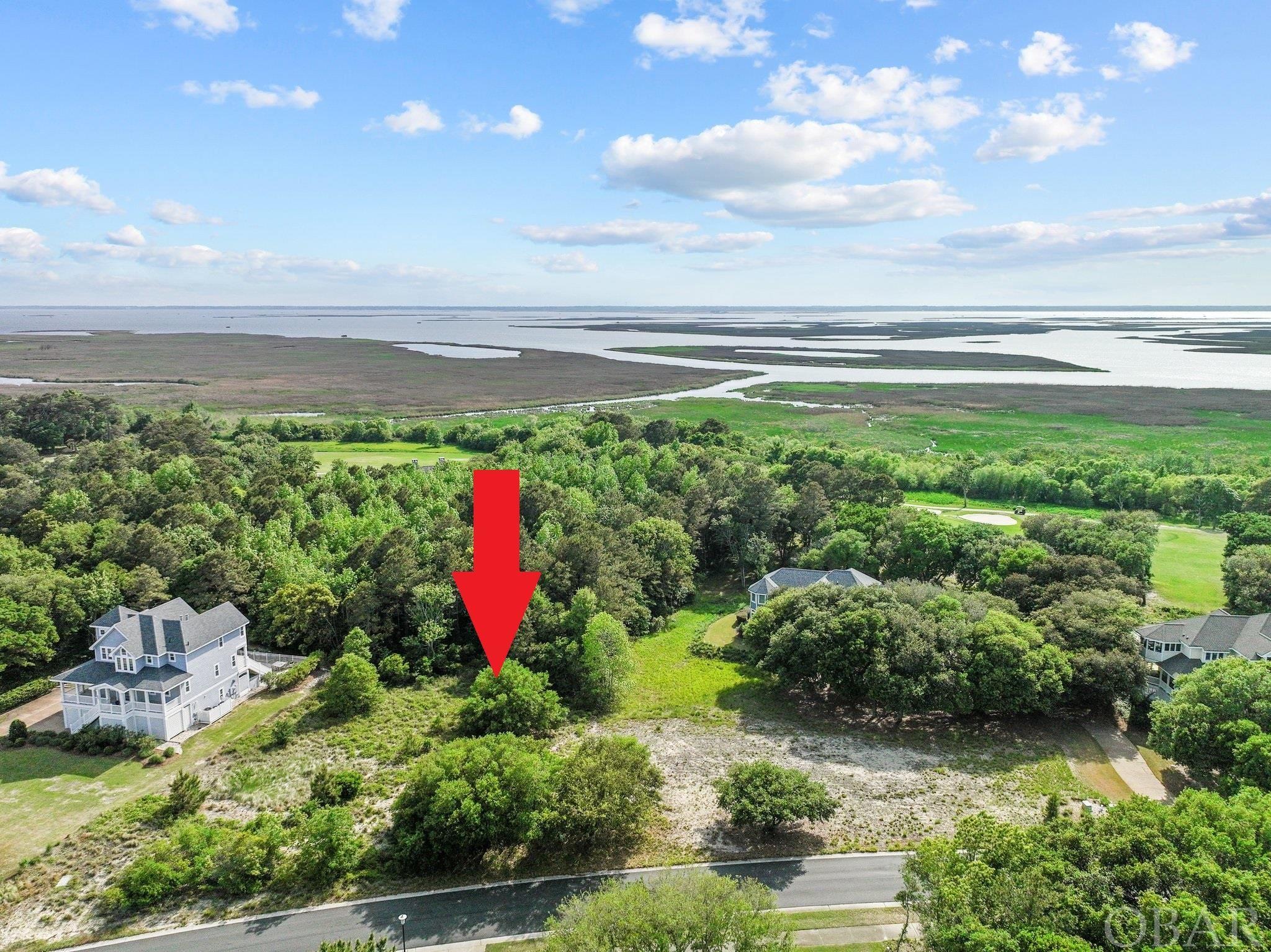 If you cannot find a perfect home for you and your family, there is an option - consider building one! This huge lot in The Currituck Club, Corolla NC may just be the place for your next beach home. If you are not familiar with this premier, gated community that stretches alongside The Currituck Sound, you will find that it is beautifully landscaped and offers amenities for everyone in the family. There are three community pools, a fitness center, basketball court, shuffleboards, tennis courts, in season trolley service that can take you to the beach access and in season valet service. Not to forget, a world-class golf course designed by the legendary Rees Jones that will satisfy any golf enthusiast.  The lot can offer you exactly what you are looking for as far as privacy and possibly sounds views. It is located between the 16th and 17th hole and you would be guaranteed not to have any dwellings between the lot and The Currituck Sound. It is also in X flood zone, which means that the flood insurance will not be required. Corolla is the ideal vacation destination for families who are just as happy lounging on the beach as they are indulging in an afternoon at the spa. Come and see for yourself if this is the place where you can start making your own Outer Banks memories.