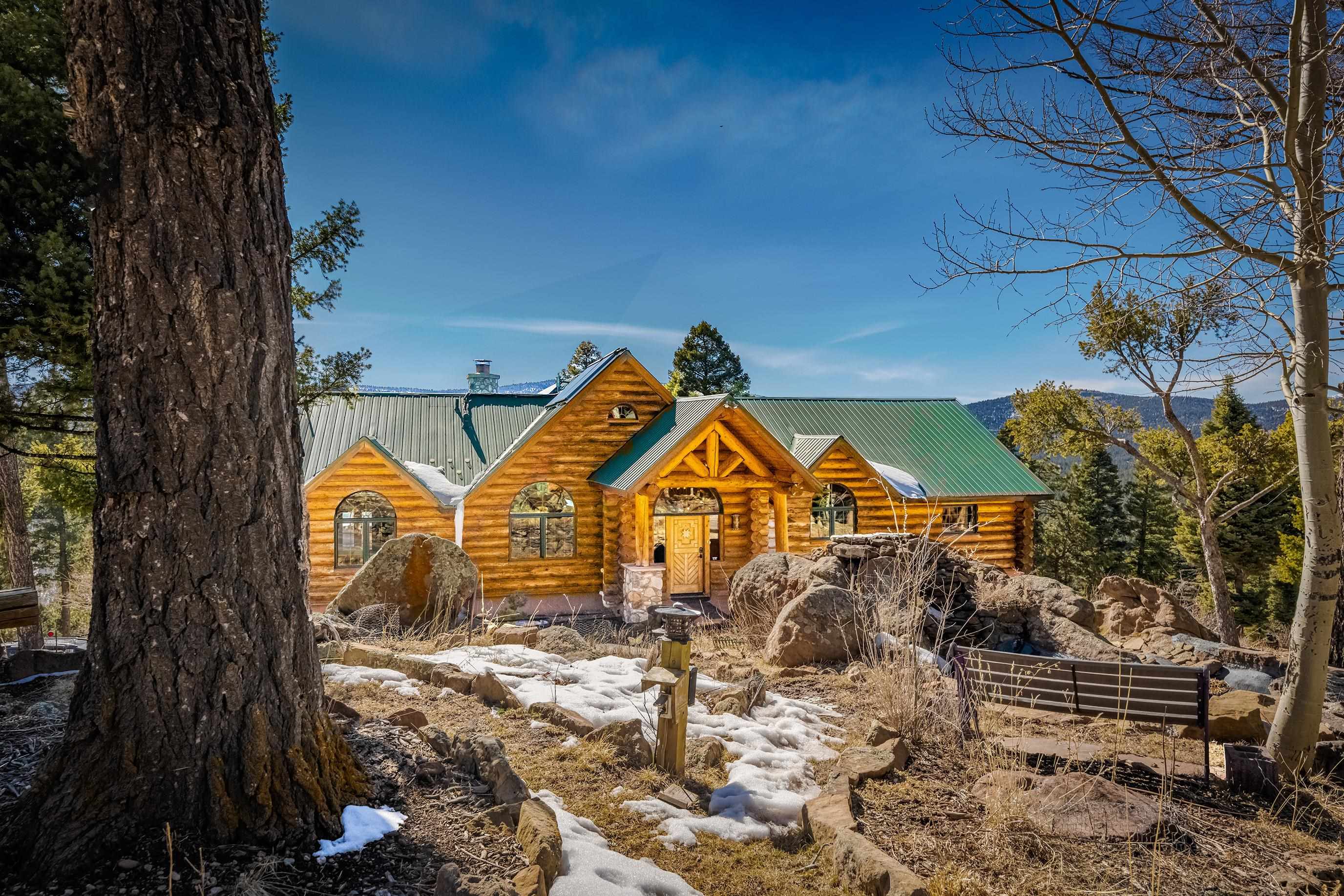 Luxury Log Cabin with Amazing Valley Views! This beautiful custom home is located at the end of cul-de-sac conveniently bordered by 144 acres of designated greenbelt but still just minutes from the the ski mountain. As you enter the home you will notice the soaring viga ceilings and the clean tiles laid throughout. A great open floor plan plus a built in wet bar and pool table make for a perfect hosting area. There is also a wall of Pella windows revealing spectacular views of Wheeler Peak and beyond. The kitchen is complete with granite countertops and a custom designed island. There is a separated dining area accented with decorative wooden beams. The master bedroom features a gas kiva fireplace and private entrance to the deck containing a large hot tub as well as dramatic latilla and viga ceilings. Downstairs contains an extra living area, a mini kitchen and two more bedrooms. Bonus features include fiber-optic internet, solar panels and a fully paved driveway for added convenience and efficiency.