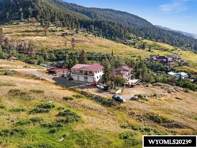 Nestled in a small valley just below the falls stands this marvelous 7400' home with Garden Creek tumbling and laughing down the property line just below nearly 2000' of wrap around deck. Enter the 900' living room with Bamboo floors, walls of windows, spectacular views and a gas log fireplace and you're in entertainment paradise. Video Tour Link: https://youtu.be/GFfE8cvNAJw The magnificent kitchen offers custom knotty Alder cabinetry with a ton of storage and a 16' x 6' island with a cook-top, a popup-exhaust system and it's own hand sink. All this is covered with granite countertops. There's even "clean" and "dirty" dishwashers. Two steps up leads to a cozy den with more windows and a fireplace. Two bedrooms and a large 3/4 tile bath round out the main floor Up the stairs to the right you'll come to the Master Bedroom with Mahogany floors, custom cabinets, another wall of windows with access to the balcony over the main deck and it's own fireplace. The Master bath features a large corner tub, separate vanities, a walk in shower and a walk in closet. This bath, as do all the baths, comes with radiant heated tile floors. If you turned left coming up those stairs you would come to a colorful sitting room with another full bath and bedrooms #2and #3. There's also another door into the MBR. Back down the stairs and just off the kitchen you'll find a tiled Rec Room with it's own full bath and, of course, lots of windows including one that's shared with the kitchen. Out thru the Laundry room and up the ramp to an enormous three car+ garage with it's own furnace and, lo and behold, another full bath. Climb the stairs out of the garage and you'll enter a humongous Great Room with a bar you can customize into a another kitchen or a king-size serving area. Two more bedrooms reside up here as well. split by a bath with separate tub and shower. areas. And, imagine, there are windows on all four sides of this multi-use additional space. There are numerous skylights, a 2 car detached garage with shoparea for the home handyman. There's also a 2 car carport under the front deck. And if you're into wildlife deer, turkeys and Magpies are plentiful and hummingbirds galore will grace your feeders in the summertime. This awesome, low mountain home with spectacular views in all directions lies just a few minutes from the ski area, and ten or so minutes from downtown Casper. This completes our tour. I hope you have enjoyed it!! Call Joe Carson @ 307-267-6986 and let him know you want it.