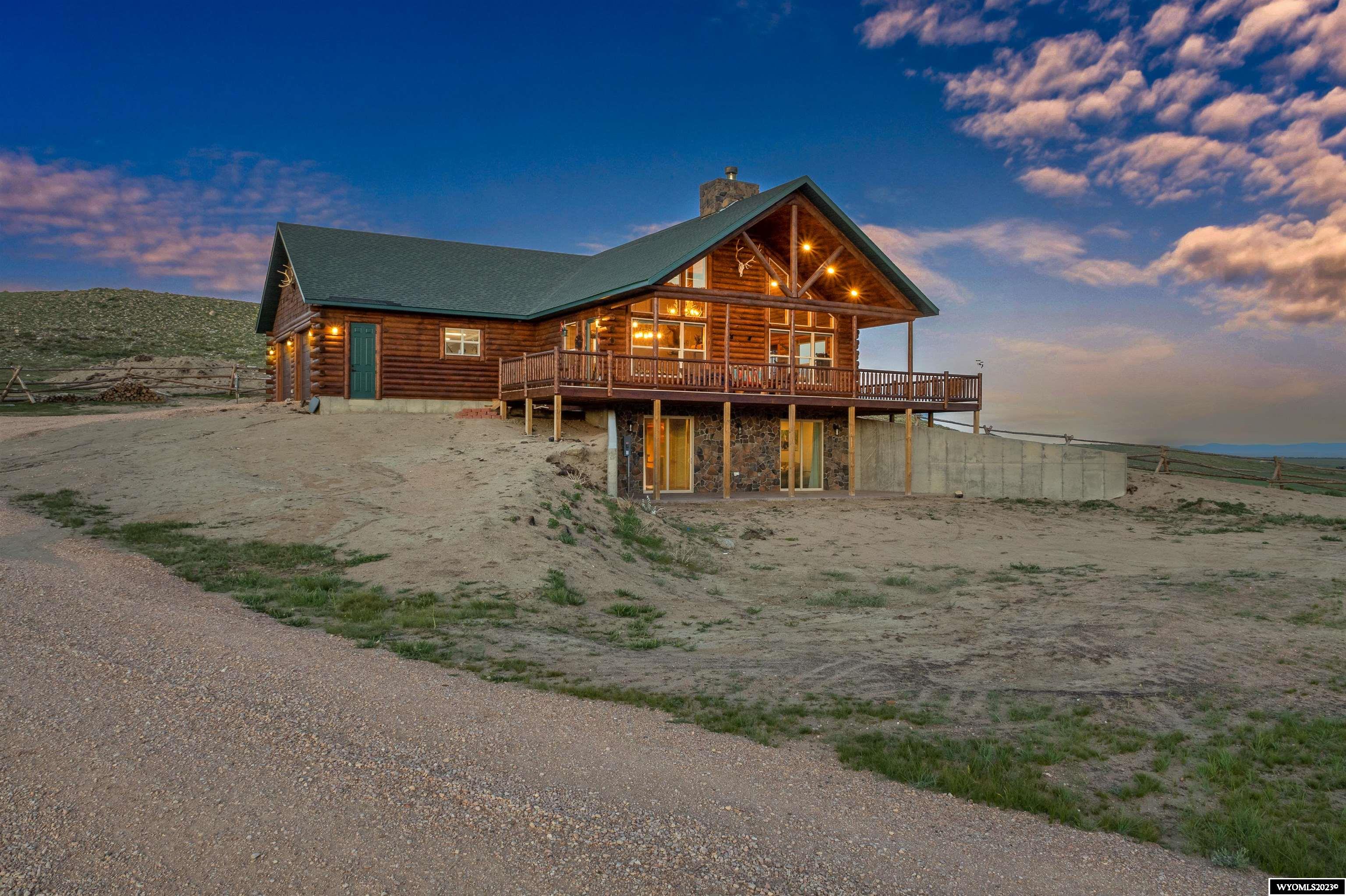 Breathtaking new log home in Wild Horse Ranch with beautiful mountain views! Built in 2021, this 2900 +/- sq ft home boasts direct views of the Medicine Bow National Forest and Lake Hattie just minutes from Laramie. Bordering 240 +/- acres of National Forest to the north and west, you'll have plenty of room to roam and no close-by neighbors! The beautiful custom home features a spacious master bedroom suite on the main floor while the walk-out basement holds an additional 3 bedrooms and large lounge area. Top of the line Kitchen-Aid kitchen appliances and an on-demand reverse-osmosis system with beautiful kitchen cabinetry and countertops compliment a cozy rustic design scheme .The main level open floor plan lends to spacious entertainment opportunities around a huge stone fireplace with tremendous western views through. Utilize the wrap-around deck on cozy evenings watching the sun set over the mountains just across the valley. Located in the northwest corner of the property is the last-remaining original settlers cabin in the area, which has been utilized for picnics, relaxing, and even as a hunting blind. The area holds deer, antelope, and the occasional elk, with nearby public hunting opportunities in Wyoming Game Units 9 (elk resident general), 76 (deer resident general), and 45 (antelope draw).Additional conveniences include a pet wash, pet door/turnout area, 50 amp RV connections, landscaping, patio and more.  Tons more to learn about this magnificent opportunity to step into a beautiful new build in the peace and quiet of Wild Horse Ranch. Contact Land Specialist Drue Meyer to learn more and set up a private showing!