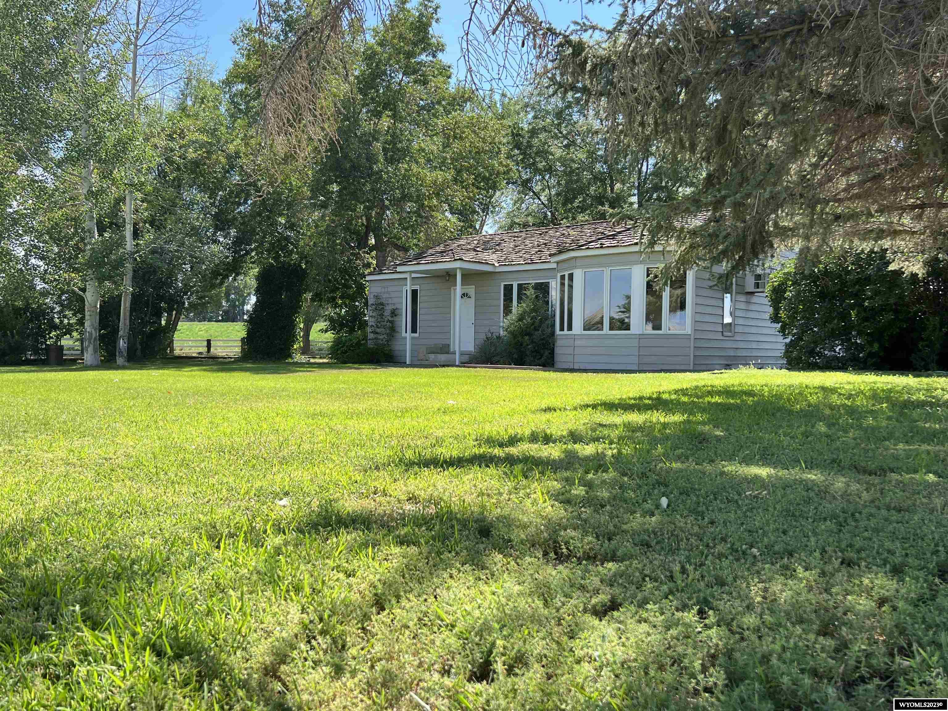 Views, comfort, trees, and SPACE! This 37.55+/- acre farm is one of a kind! You will be hard pressed to find another on the market with so much to offer. The fields are currently planted with grass/alfalfa hay and farmed by a neighbor. Behind the home is a 30'X40' shop with power. Beyond the shop is a set of corrals complete with a loading chute and feedlot setup.  The (mostly) updated 2 bed, 2 bath home with 2,632 SF living space has beautiful views all around with large rooms, one updated bathroom, and a huge mudroom. Watch the sun rise over Cloud Peak and the Big Horn Mountains while you sip your morning coffee through the huge bay windows in the dining room. The sunken sun room makes a perfect place for lounging or entertaining with concrete patio of the sliding door.  Just off the sunroom is a cozy den with an open hearth fireplace. Original hardwood floors have been refinished in the majority of the home and there is a partial basement area that could be finished into additional bedrooms or left as is for storage/pantry space.