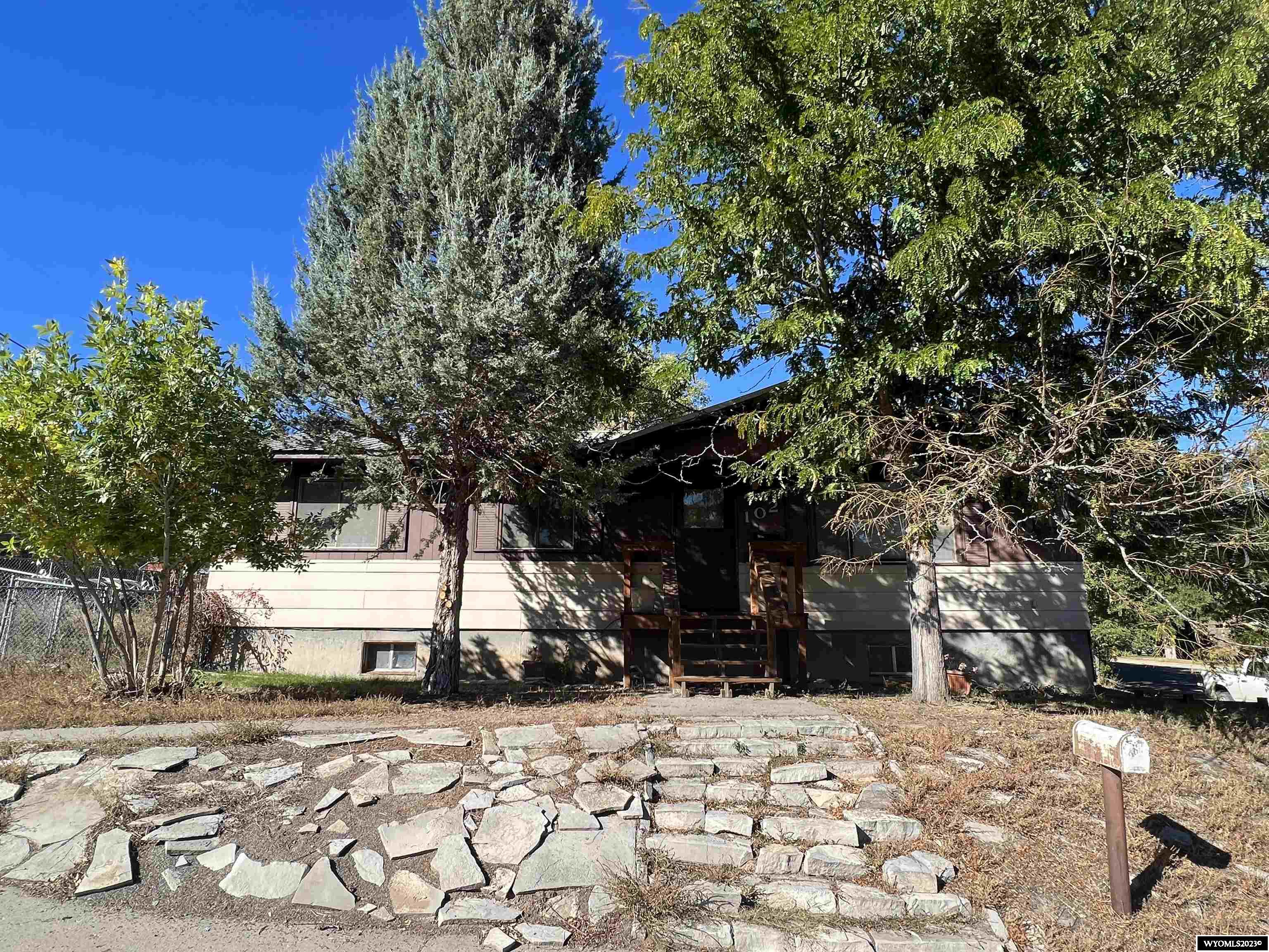Elevated ranch-style home in a great location with lots of potential!  3 bedrooms all on the main, with an extra 1/2 bath off of the primary bedroom.  The full basement offers a clean slate for new owners to create their own customized space.  Plumbing is roughed in for a basement bathroom.  "Tuck-under" single garage bay offers convenient access into the home, and adjacent workshop could also be converted into another garage bay.  Durable metal roof and newer front deck are exterior highlights. Yard is completely fenced with chain link, and garden area is fenced separately.   There is also a parking area off the alley for "toys" or a smaller RV.  Property is offered in "as-is, where is" condition.  Any lender-required or other repairs will be buyer's responsibility.