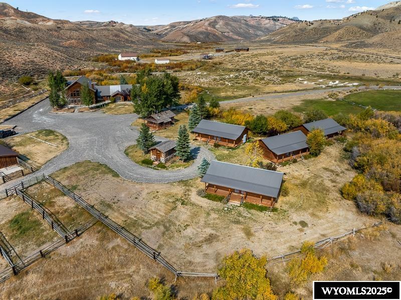 Waterfront Acreage >  Along the serene Horse Creek, this ranch offers natural beauty and endless opportunities for recreation and relaxation. With a total of 8 buildings and mountain views, this property borders an additional 35-acre and 80-acre lots, both of which are available. The windows throughout the lodge show off the mountains and the river valley, which are best appreciated at the ever-changing sunrise and sunset. The living areas are flooded with natural light, which creates a feeling of warmth all day long.    Only a 10-minute drive to downtown Dubois and to the North, you’ll find millions of acres of public land to explore forests, rivers, lakes, and mountains. Perfect for hiking, horseback riding, or any outdoor adventures. For grander excursions, Grand Teton National Park and Yellowstone National Park are approximately an hour away.  The Lodge: 7,700+ Square Feet of Rustic Elegance   This magnificent lodge is a blend of grandeur and Western charm. Key features include:  The Great Room: Vaulted ceilings, a floor-to-ceiling fieldstone fireplace, custom windows and sliding doors, wooden floors, chandeliers, and an open staircase. Beyond the grand entry is a cozy multi-use room that can be used for a private dining experience, a meeting room, or be turned into an additional bedroom.    Upper Level: The staircase leads to an intimate social area with a wet bar, fireplace, and half bathroom, plus a conference room with its own fireplace, storage areas, and outside access.   Commercial Kitchen: Fully equipped with a large exhaust hood, stainless steel sinks, a large pantry, and ample prep space.    Potential for Events: The lodge’s large deck provides a picturesque setting for weddings, family reunions, or other special events.    The laundry space is conveniently located at the back entrance for guests or staff. Across the hall from the laundry is a mud room with storage, cabinets, dishwasher, and a half bath.   The living quarters in the lodge feature:  - A vaulted living room with a fireplace. - A dining area leads to a large wooden deck with railings and mountain and river valley views. - A private kitchen - Upper-level bonus room. - Three bedrooms with ensuite bathrooms, one of which stands out with a fireplace, sliding patio doors, and breathtaking sunrise views over the river valley.  - A guest bathroom. - A business center with cabinets, counter space, and outside access can be turned into an additional bedroom.  The Office or Conference Center: 1,400 Square Feet of Versatility   This building features custom cabinets and workspaces with:  - Two rooms serve as private offices and can be converted into bedrooms.  - A finished storage area leads to a corner room with large windows and a fireplace, used for for private conferences.  With the layout, this structure could be utilized as a two- or three-bedroom home.  Guest Housing: Four Duplexes for Comfortable Accommodations  Built in the late 1990s and used sparingly, these four duplexes each include a front porch, one large bedroom, and another bedroom with a private entrance.    Built on concrete blocks and three-plus feet deep crawl spaces, where electric heat and water heaters.  Stables, Outdoor Pens, Arena  - Three indoor stalls with feeders, individual doors, and side wall skylight. - Seven gated pens, two large corrals, six stock tanks, and a working chute for livestock grooming and care.  This area is designed with functionality and comfort, perfect for horse or livestock operations.  Experience the Absaroka Mountains   The Absaroka Mountain Range surrounds the property, offering stunning views and endless opportunities for outdoor adventure. Whether you’re looking for a private retreat, event center, or working ranch, Horse Creek Ranch delivers an exceptional experience.