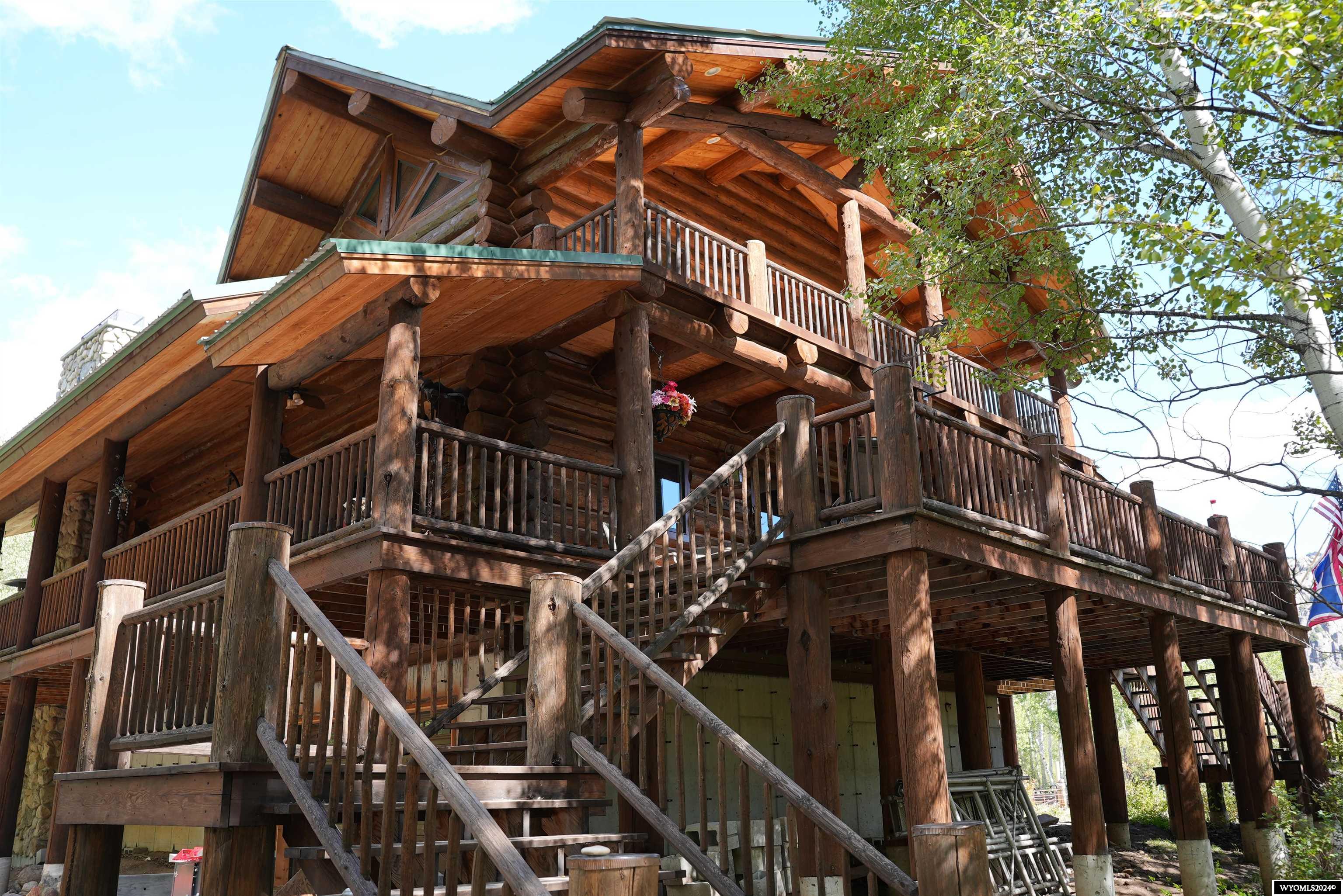 This log home is set in a tranquil natural environment. The main house features 3 bedrooms and 3 bathrooms, an expansive kitchen with a breakfast nook and two large seating areas each with its own fireplace. The high, vaulted ceilings add to the homes grandeur, and the den off of the primary bedroom offers a private retreat. Additional amenities include a large garage with ample storage, radiant heated floors and a utility room with a washer and dryer.  With its spacious layout, rustic charm, and modern amenities, it offers a perfect retreat surrounded by the beauty of aspen trees, the Bridger National Wilderness and Boulder Creek. There are outdoor features like a fire pit that enhances its appeal, making it not just a home but an inviting escape into nature. The property sits on 2.37 acres of beautiful woodland, providing a sense of seclusion and tranquility. Along with the main house, there are three guest cabins, perfect for hosting visitors. This home offers a perfect blend of rustic charm and modern comfort, creating a truly wonderful place to retreat.