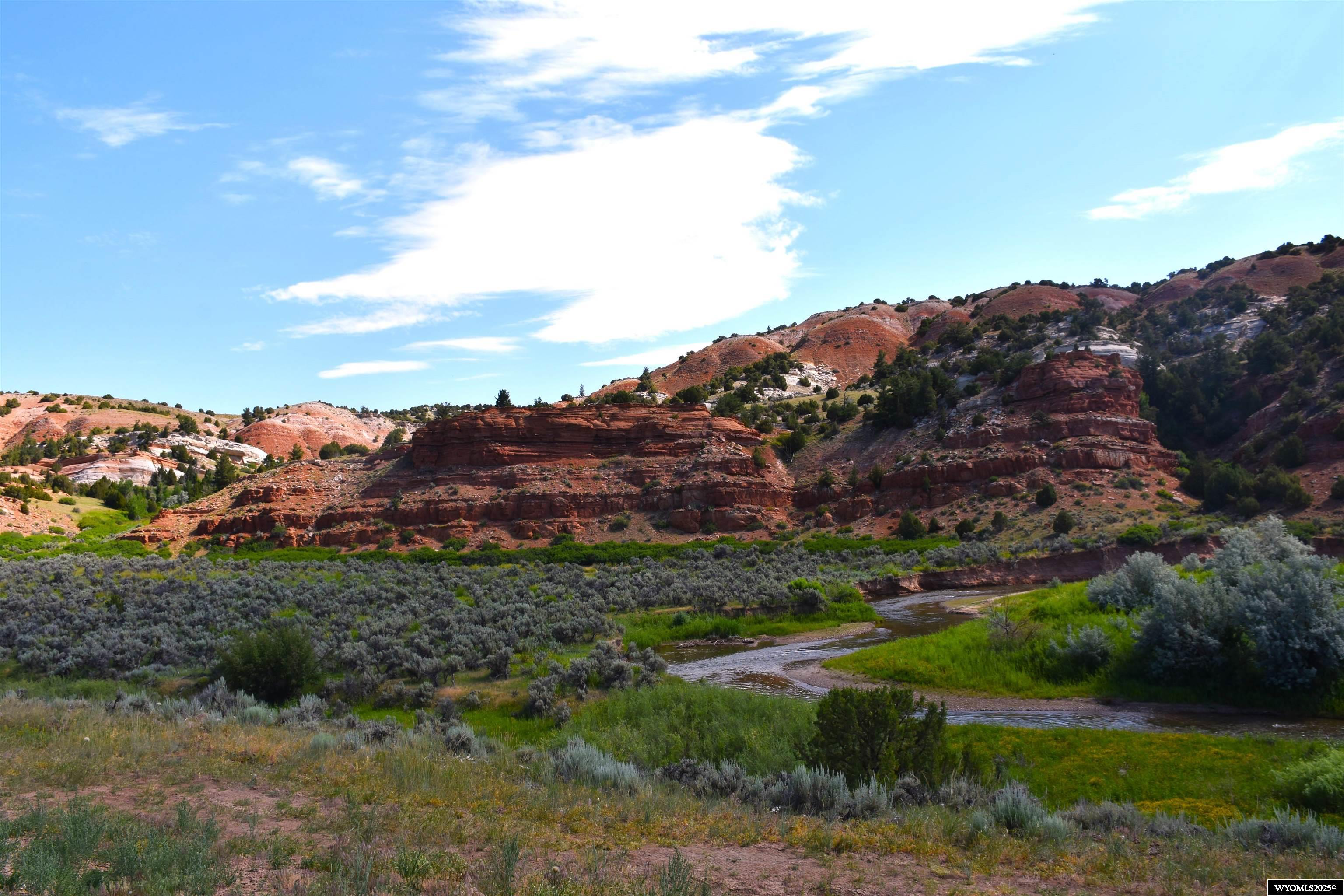 Every once in a while, we list a rare gem. This is it!  Take advantage of this incredible and rare opportunity to own Wyoming river front property. This hidden gem offers 200 acres of Wyoming range land with varying terrain of red cliffs, canyons, riparian areas, river frontage, and a natural spring. You will enjoy years of exploring this vast variety of habitats suitable for many of Wyoming’s wildlife needs.  The roadway access to the property has been newly built and graveled for year-round access. Improvements for your comfort on the property include an RV structure, complete with roof, wastewater dump to a permitted septic, and fresh water from a 7500-gallon cistern. The RV pad was structurally planned and built to accommodate your future ideas for completion to a totally enclosed building for a shop or home. Included in the RV Parking structure is a modern “bathhouse”. Every comfort you would expect in your home bath is here.  The property is newly fenced with barbed wire on three sides with only the top of the red rocks fence line left as original. If you look across the river, in the red rock cliffs you will find a natural spring creating a dense “green” area. Sellers have hiked much of the land and are always amazed at what they discover in those hills. The historic use of these lands is apparent. They were surprised by the many areas of level terrain found among the red rock cliffs and outcroppings. How about an overnight camp under the stars? The current owners have identified a beautiful area along the river which they felt would make a stunning homesite.  It is marked and we will share that with you when you view the property. There are also areas they can recommend for easy crossing of the river. There is a bridge on the Dallas Dome oilfield site that gives legal access to this subject property to the parts of the land that are across the river. This is a fantastic and very special piece of Wyoming land. We think you should see it for yourself. It may be too good to last too long. Call for an appointment to see!