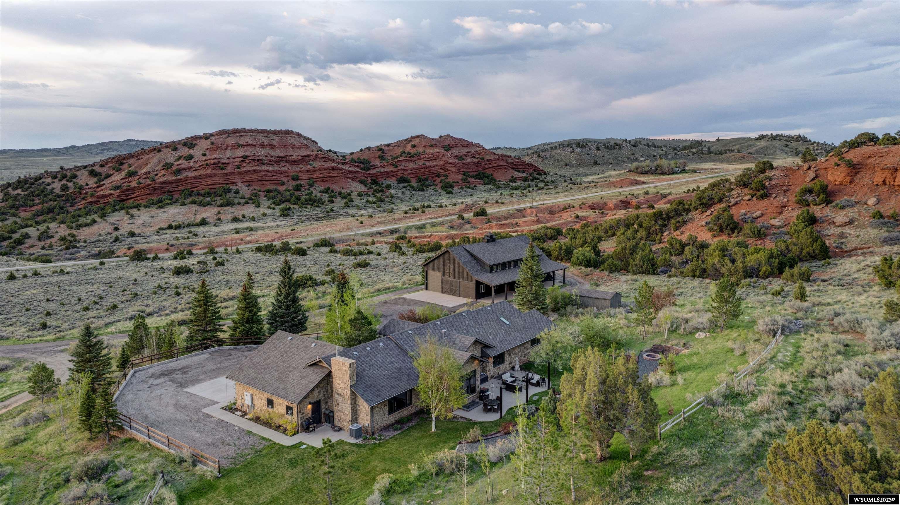 A property like this one does not come on the market very often. Over 46 acres of beautifully landscaped and thoughtfully developed land, offering privacy, peacefulness, quiet luxury and exceptional craftsmanship. Set against a backdrop of panoramic mountain and valley views, with close access to world class fishing and only 9 miles into town, this 5-bedroom, 4-bathroom, fully furnished, ranch-style home offers 5,260 finished square feet and was fully remodeled in 2011 with high-end finishes throughout.  The main level features vaulted ceilings and reclaimed Kentucky oak barn wood flooring, triple-pane Pella wood windows, a custom Pella front door and a gas fireplace with a hand crafted oak mantle. The kitchens functional layout and clean design include custom alder cabinetry, sanded concrete countertops, Wolff and Sub-Zero appliances including wine fridge, double oven and 6 burner stove.  The entire home is managed through the Lutron smart lighting and sound systems. The primary suite includes two custom cedar walk-in closets, a spa-inspired bathroom with heated floors, an oversized soaking tub, both rain and standard shower heads and access to the large teak wrap around deck. Additional highlights include pine-framed glass privacy doors, a guest bath with skylight and heated floors, and a spacious mudroom with laundry, utility sink, storage, and custom concrete countertops. A dedicated office space with in-floor outlets and sliding barn doors adds to the home’s functionality. The lower level offers three additional bedrooms, two full bathrooms (one ensuite), two large living areas, and a media or flex space. The oversized storage room and mechanical systems—including tankless and tank water heaters, a water softener, and dual access to the attached heated garage—emphasize both convenience and thoughtful design. The heated three-stall garage is accessible from both the mudroom and basement. Home also includes a whole house generator. The 5,184 sq ft modern barn includes a main level with two drive-through bays, one with 12’ barn doors and one with 14’ overhead doors, a pine-paneled main level space, reloading room with teak built-ins and a commercial sink, bathroom, and an additional 2,592 sq ft vaulted loft. The loft is insulated, drywalled, and features eight large Pella windows, a west-facing balcony, and is plumbed for a second bathroom, perfect for events, a studio, guest quarters, or additional workspace.  A 576 sq ft covered concrete pad expands the potential for RV or boat storage and entertaining space. Additional outbuildings include an insulated garden shed and multiple workshop-ready areas with 240V power. The land itself features a private gravel road off Goose Egg Road, a spring-fed water source running through the property, a private 700’ well, and an updated, expanded septic system. The landscaping is extensive, with full irrigation, fenced raised-bed gardens, a large fire ring, and several inviting outdoor living areas. Truly rare for the Casper area, this estate offers a harmonious blend of casual sophistication, smart home technology, and luxurious amenities, ideal for anyone seeking space, peace, and timeless quality in one complete and unique package. Call Claire Marlow with REMAX The Group to schedule your private tour. 425-753-5617
