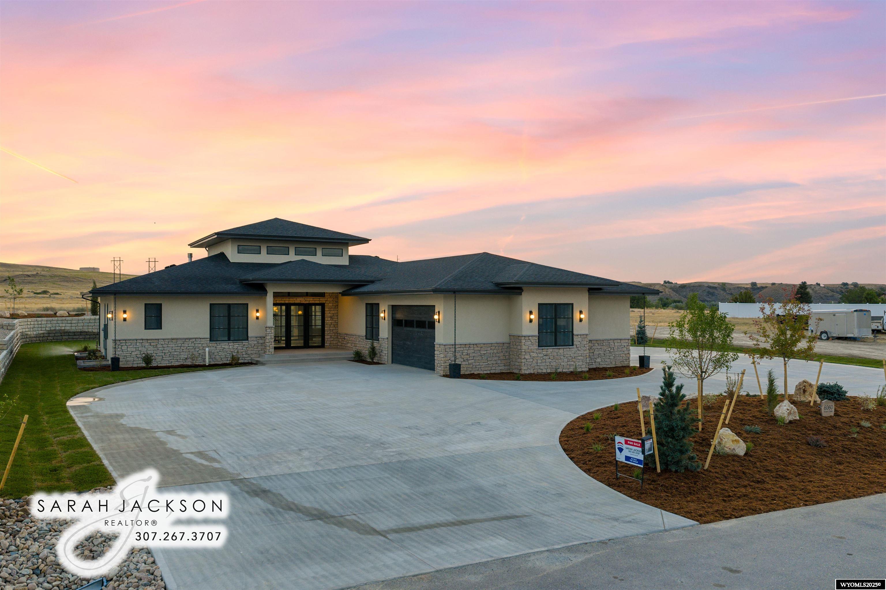 Experience refined luxury in this one-of-a-kind custom home crafted by Mountain View Builders, Inc. This stunning Modern Prairie residence offers a total of four bedrooms and 4.5 bathrooms, with a generous 2,669 sq. ft. on the main level and boasts a sleek exterior with elegant stone accents and transom windows that invite abundant natural light into every corner. Exposed steel beams gracefully span the ceiling of the great room, enhancing the modern aesthetic while defining an open, airy space. Oversized glass doors seamlessly connect the living area to the back patio, perfect for indoor-outdoor living.  The spacious kitchen features a large island ideal for entertaining, complemented by a nearby walk-in pantry for ample storage. Beneath-cabinet lighting adds an elegant touch, illuminating your workspace. The primary suite offers a private retreat, complete with a luxurious five-fixture bathroom featuring a freestanding soaking tub and a generously sized walk-in closet. Additionally, this home includes three separate bedrooms, each with attached private bathrooms and walk-in closets, providing ultimate privacy and comfort.  Two laundry rooms enhance convenience—one located in the mudroom, with laundry facilities and a utility sink, and another on the main level near the three bedrooms for ease of access. Enjoy personalized climate control with a three-zone heating and cooling system, ensuring optimal comfort throughout the home. Organize your essentials in the practical mudroom, and plan your future finishes in the already framed basement, which includes two additional bedrooms, 1.5 bathrooms, a wet bar, and a recreation room—perfect for relaxation and entertainment. The oversized heated four-car pull-through garage adds unparalleled convenience and functionality to this exceptional home.  Seller, Sarah Jackson, is a licensed Realtor with RE/MAX The Group in Wyoming.